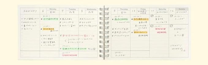 Open Mark’s Inc. A6 spiraalvormige weekplanner met handgeschreven notities, rasterindeling en kleurrijke accenten op wit papier.