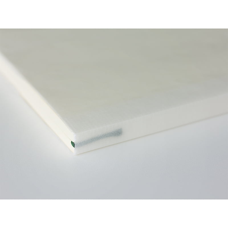 Close-up van een minimalistisch crèmekleurig Midori MD A5 notitieboek met een strakke rug en een groen bladwijzerlint.