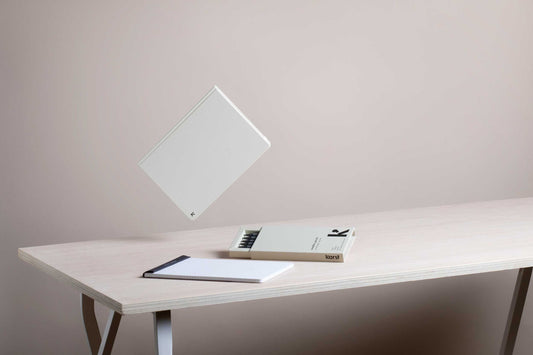 Wit karst notitieboek zwevend boven een tafel