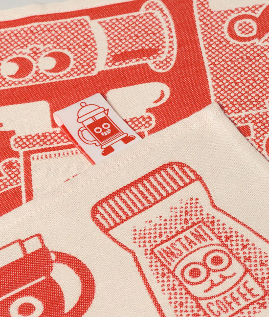 Rood en crème geweven Wrap theedoek met speelse koffie-illustraties, inclusief een pot instantkoffie en een logolabel.