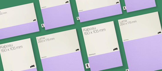 Pith Kabosu en Lumia schetsboeken in crème en lila, gerangschikt op een donkergroene achtergrond.