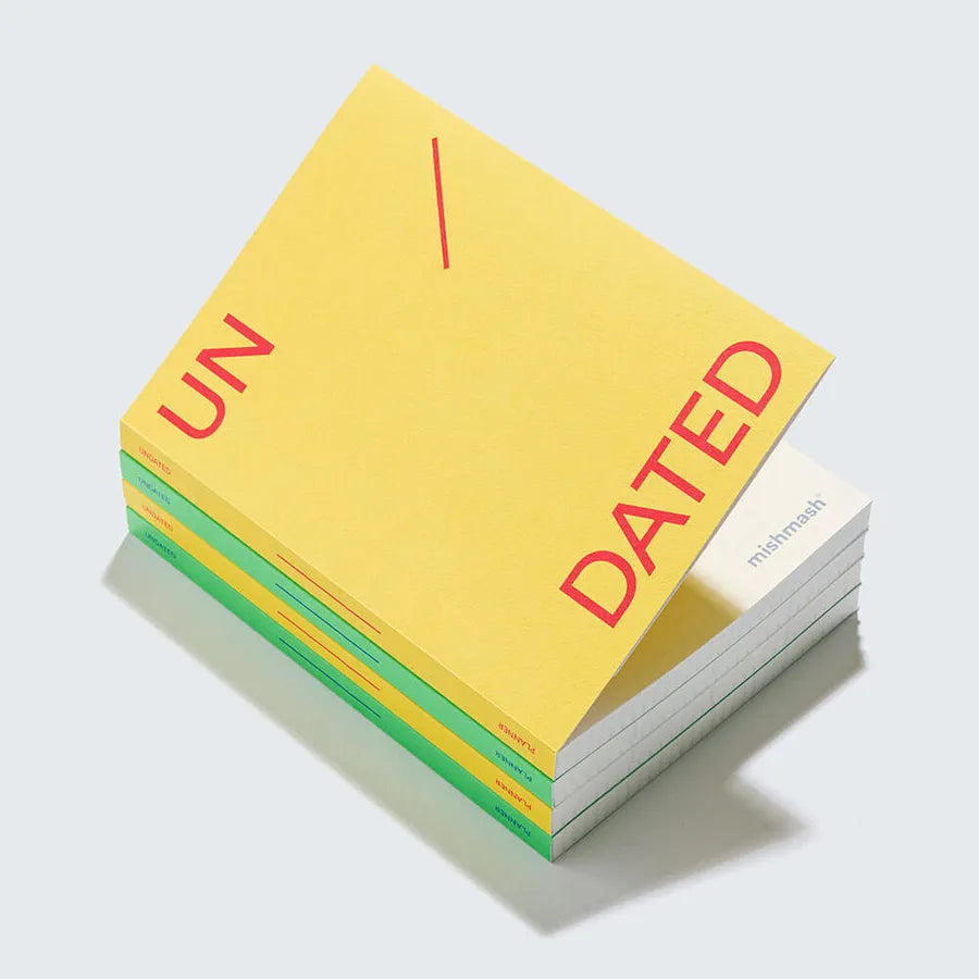mishmash Lemon A5 planner met rode 'UN/DATED' tekst, gestapeld op mintgroene en groene notitieboeken.